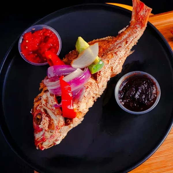 Whole fried fish topped with red onions, peppers, and avocado, served with two dipping sauces.