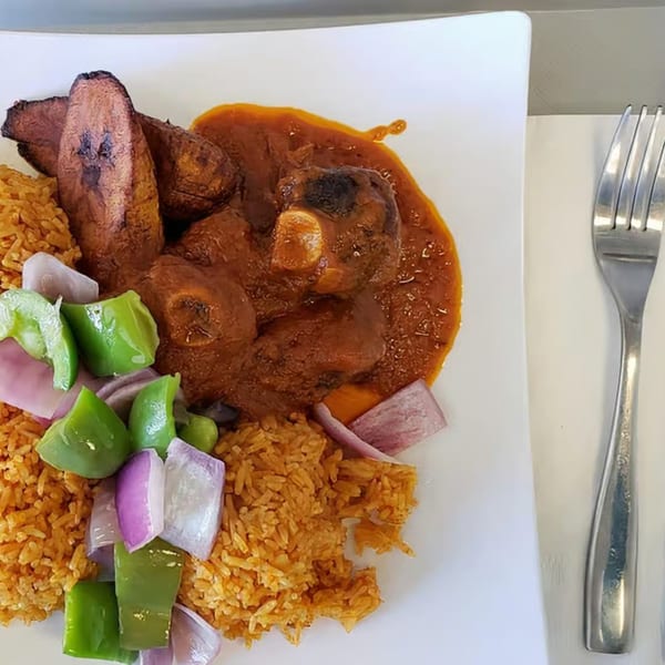 African jollof rice with stewed meat, fried plantains, and chopped bell peppers and onions.